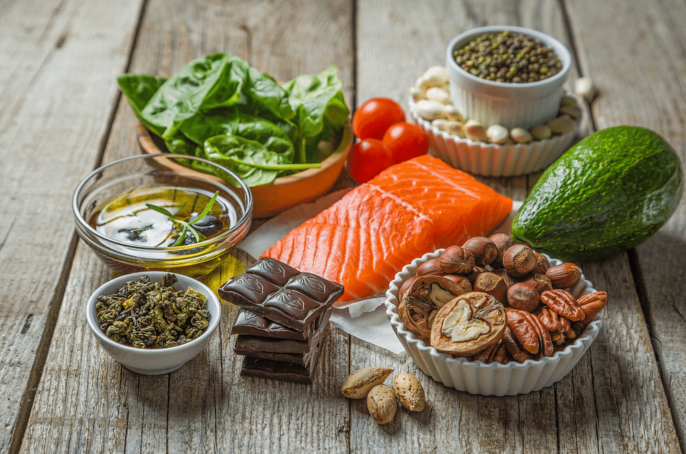 Assorted healthy foods including salmon, nuts, vegetables, and chocolate.